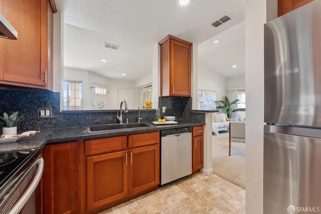 a kitchen with stainless steel appliances granite countertop a sink a stove and a refrigerator