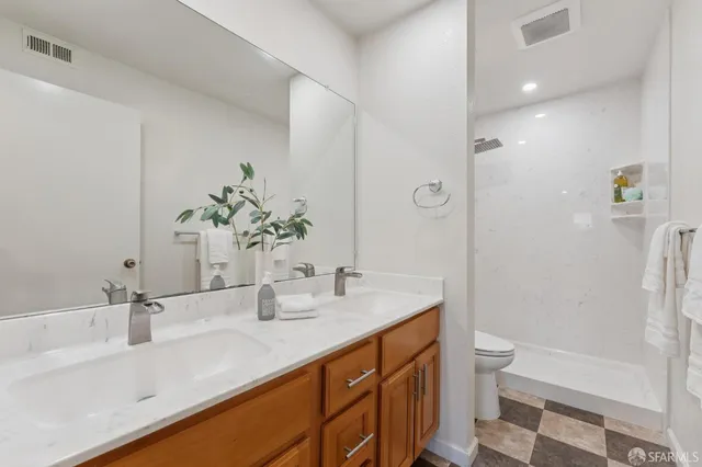 a bathroom with a double vanity sink toilet and shower