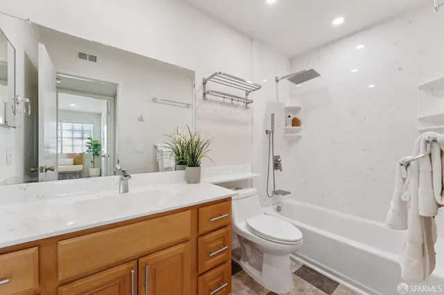 a bathroom with a granite countertop sink toilet a mirror and shower