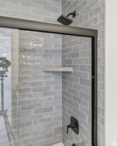 2862 South Mountain Rnch Road Cedar City, UT 84720 - Photo 41 of 64 Shower enclosure featuring subway tile, a rain showerhead, matte black fixtures, a built-in corner shelf, and a framed glass door