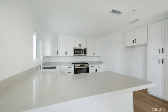 a kitchen with stainless steel appliances granite countertop white cabinets a refrigerator a sink a stove and white cabinets