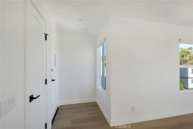 a view of a hallway with wooden floor and a bathroom