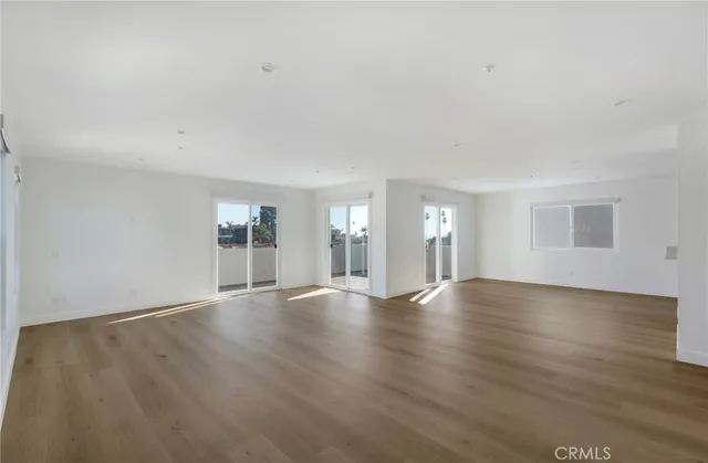a view of an empty room with wooden floor and window