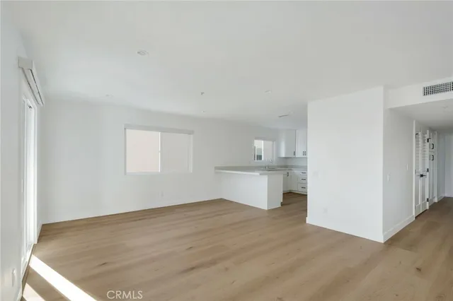 a view of kitchen and empty room with wooden floor