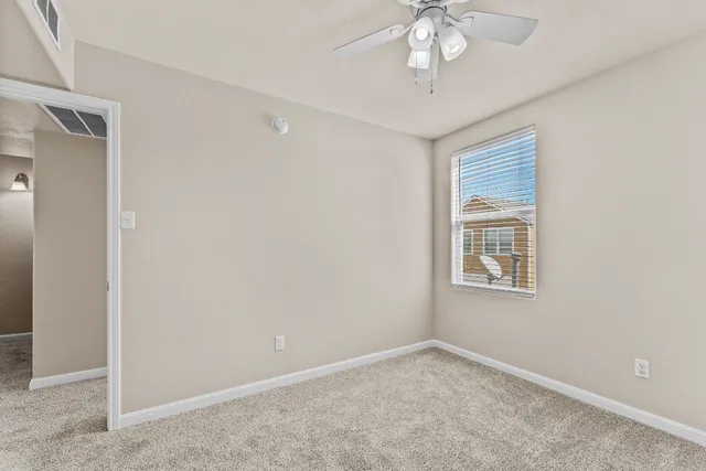 an empty room with a window and a ceiling fan