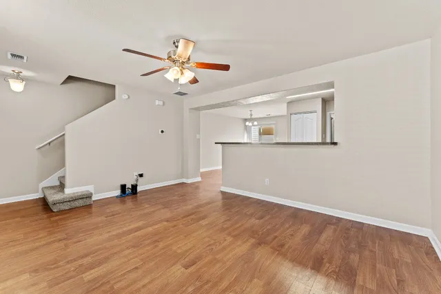 a view of empty room with wooden floor and fan