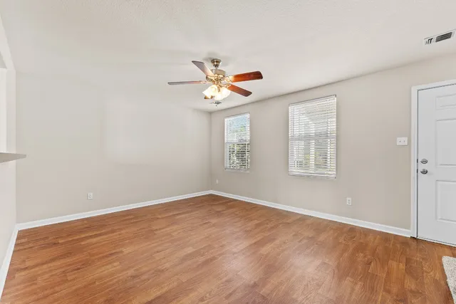 an empty room with wooden floor and windows