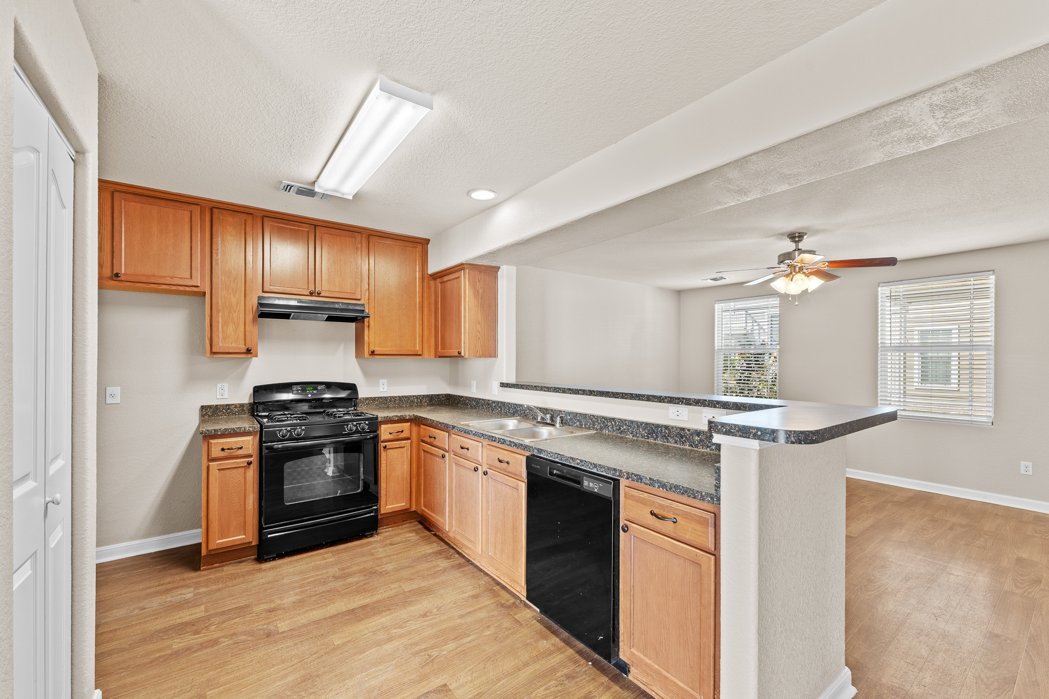 220 Trestle Tree San Marcos, TX 78666 - Photo 9 of 28 Kitchen featuring dark countertops, black appliances, light wood finished floors, a textured ceiling, and recessed lighting