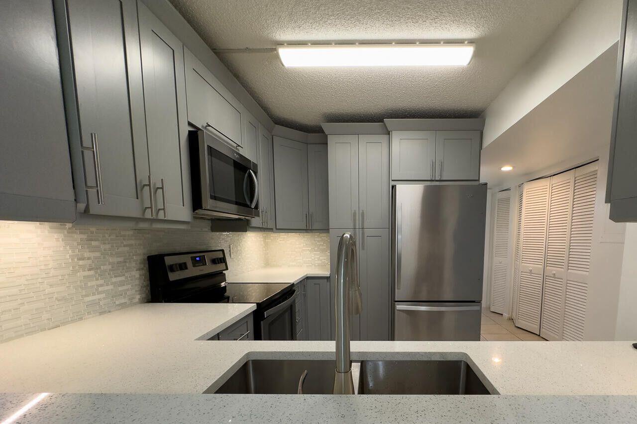 6299 Chasewood Drive, Unit D Jupiter, FL 33458 - Photo 4 of 13 a kitchen with stainless steel appliances granite countertop a refrigerator a stove a sink and a microwave
