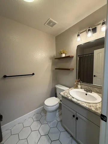 a bathroom with a granite countertop sink a toilet and a mirror