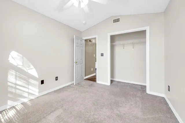 a view of an empty room and chandelier fan
