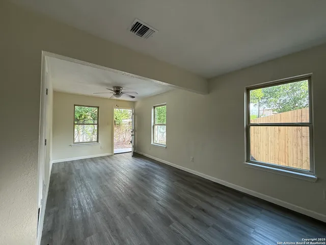 a view of an empty room with wooden floor and a window