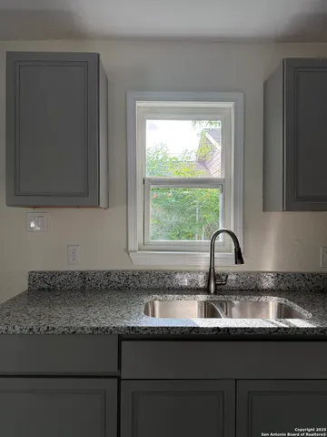 a kitchen with granite countertop a sink a window and cabinets
