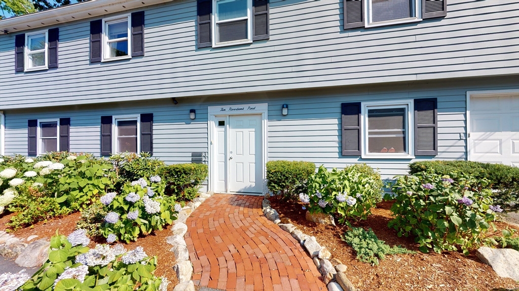 10 Riverbank Road, Unit 2 Maynard, MA 01754 - Photo 1 of 13 a front view of a house with a yard and flowers