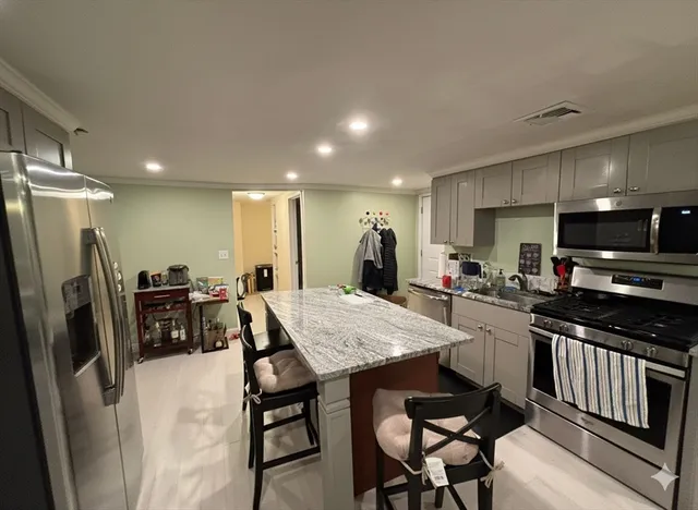 a kitchen with stainless steel appliances granite countertop a refrigerator a stove a sink a dining table and chairs