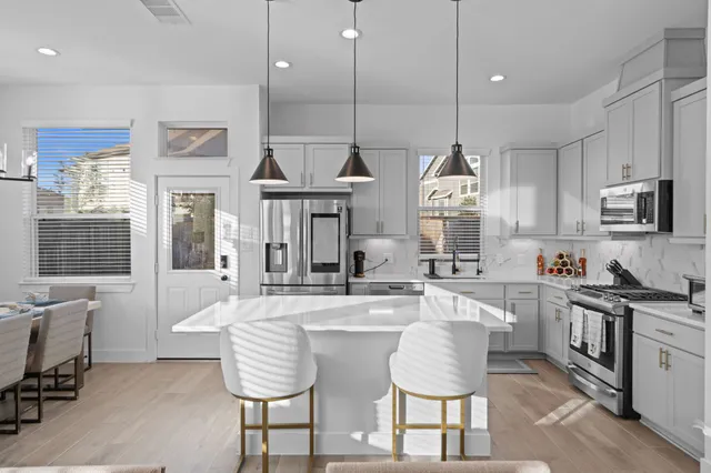 a kitchen with stainless steel appliances granite countertop a stove a sink dishwasher a dining table and chairs with wooden floor