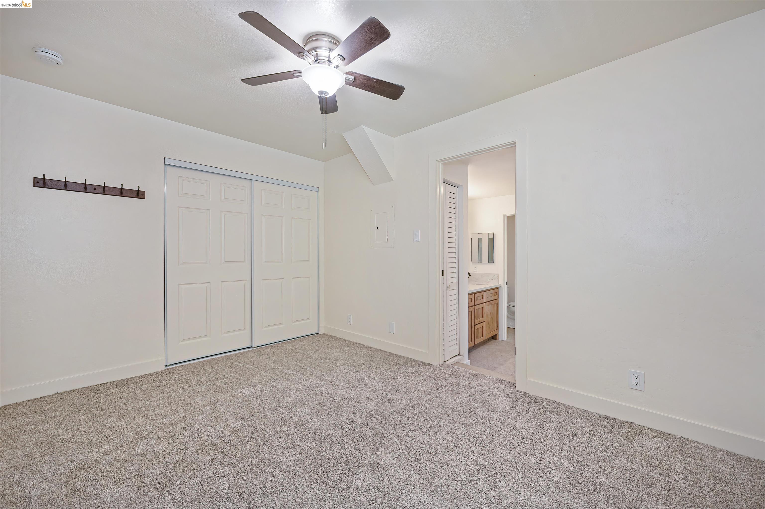 10474 Sheldon Road Elk Grove, CA 95624 - Photo 30 of 83 Carpeted room featuring a ceiling fan with integrated lighting, sliding panel closet doors, and a doorway opening to a bathroom with a wooden vanity
