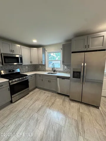 a kitchen with stainless steel appliances granite countertop a sink a stove a refrigerator with grey cabinets