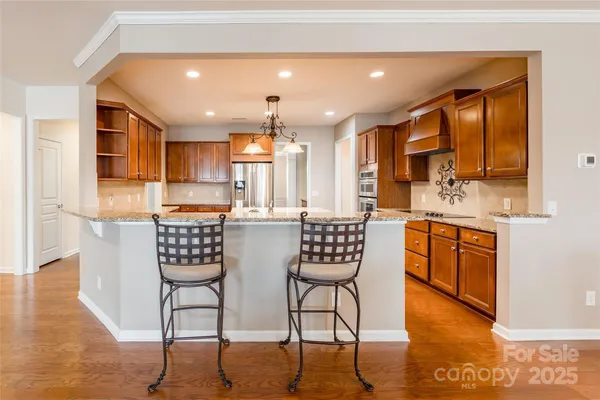 a kitchen with stainless steel appliances kitchen island granite countertop a stove a sink a dining table and chairs