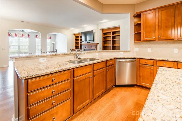 a kitchen with stainless steel appliances granite countertop a sink and dishwasher with wooden cabinets