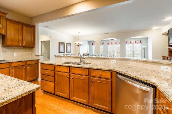 a large kitchen with granite countertop a sink and white cabinets