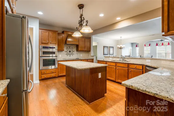a large kitchen with kitchen island a large counter top stainless steel appliances and cabinets