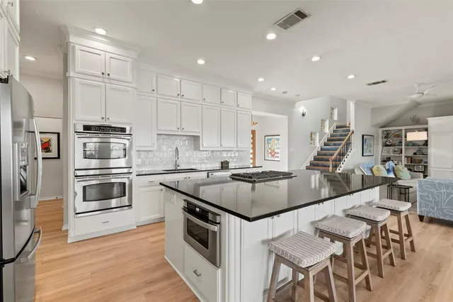 a kitchen with stainless steel appliances granite countertop a sink a stove and a wooden floors