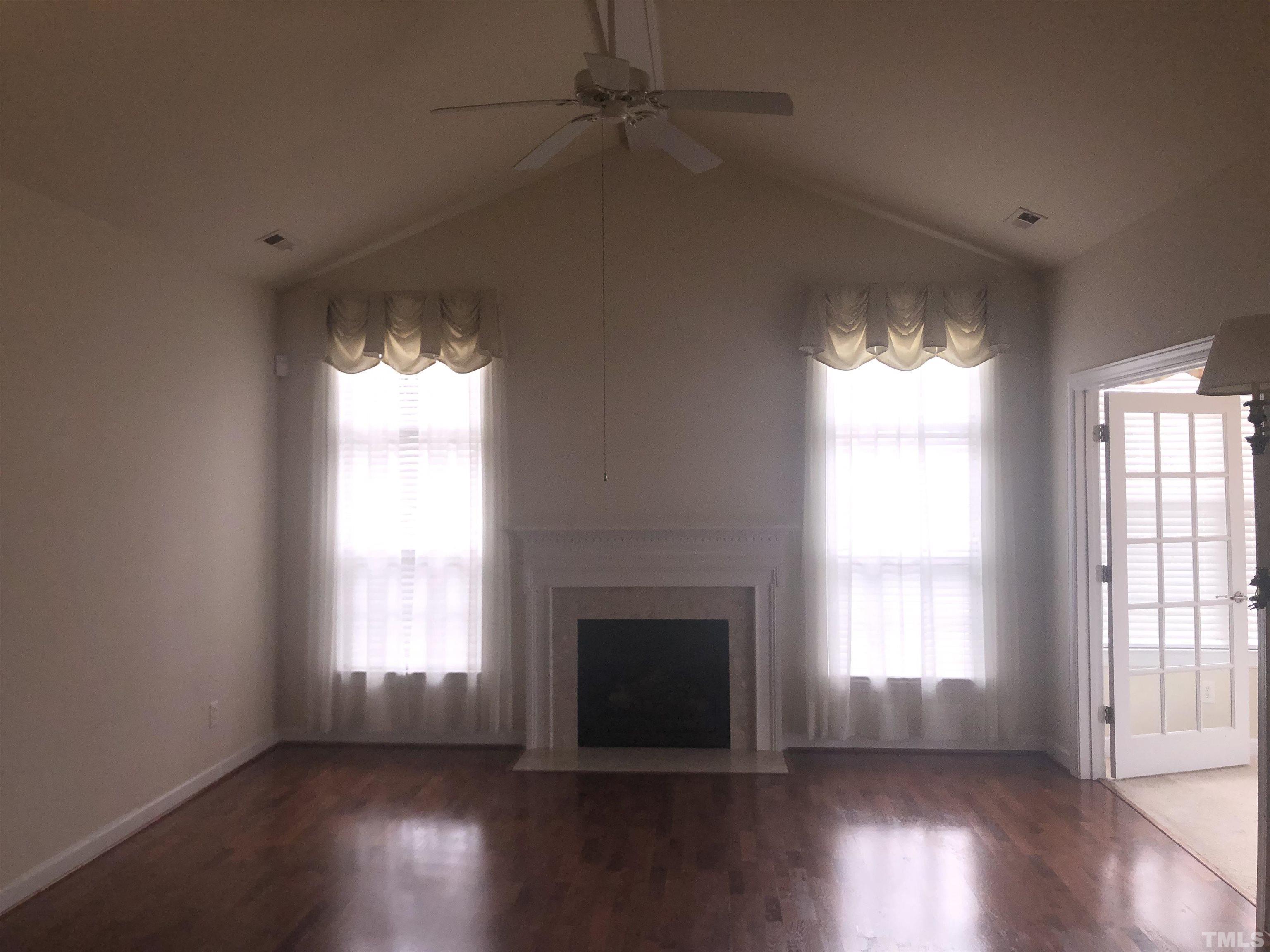 4720 Fox Fern Lane Raleigh, NC 27604 - Photo 7 of 20 an empty room with wooden floor fireplace and windows