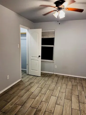 a view of a hallway with wooden floor and a bathroom