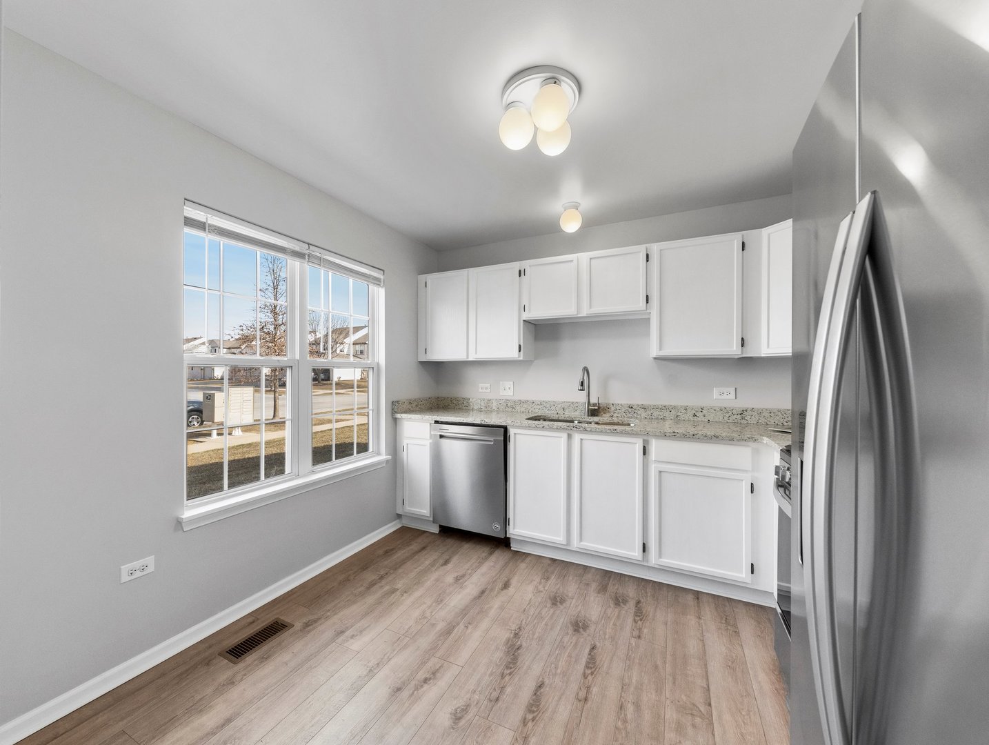 2503 Sheehan Drive, Unit 101 Naperville, IL 60564 - Photo 6 of 19 a kitchen with granite countertop a refrigerator a sink and dishwasher with wooden floor