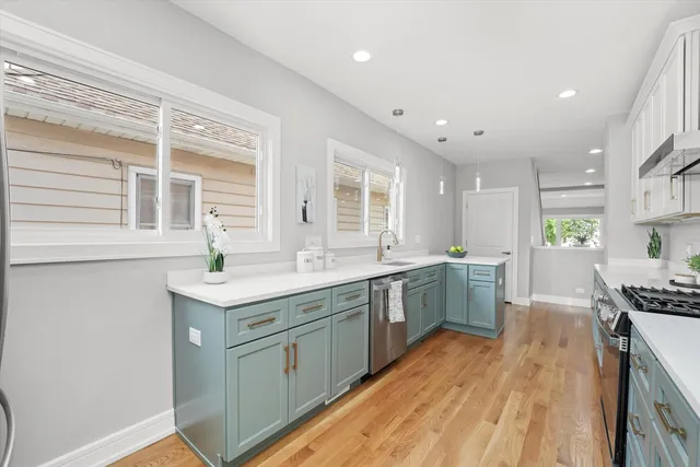 a kitchen with a sink stove cabinets and wooden floor