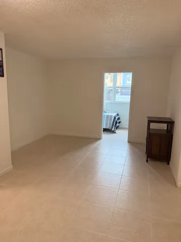 an empty room with chandelier fan and windows