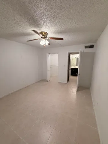 an empty room with windows and fan