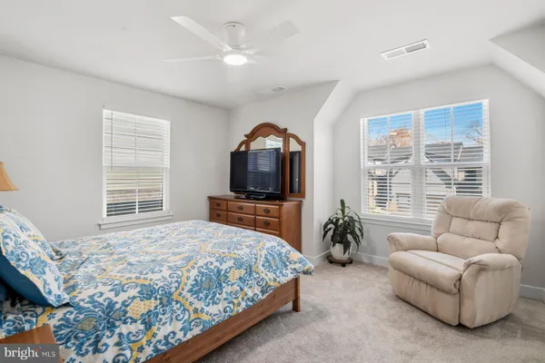 a bedroom with a bed a couch and a flat tv screen