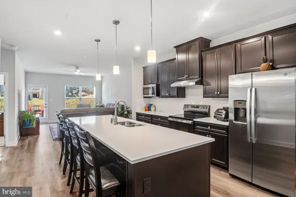 a kitchen with stainless steel appliances a sink a stove a refrigerator with wooden floor
