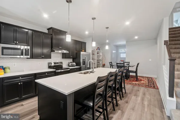 a kitchen with stainless steel appliances kitchen island granite countertop a sink a stove a dining table and chairs