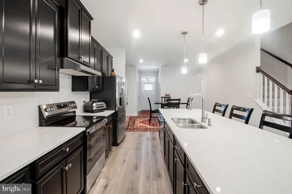 a large kitchen with stainless steel appliances kitchen island granite countertop a stove a sink dishwasher and a refrigerator with wooden floor