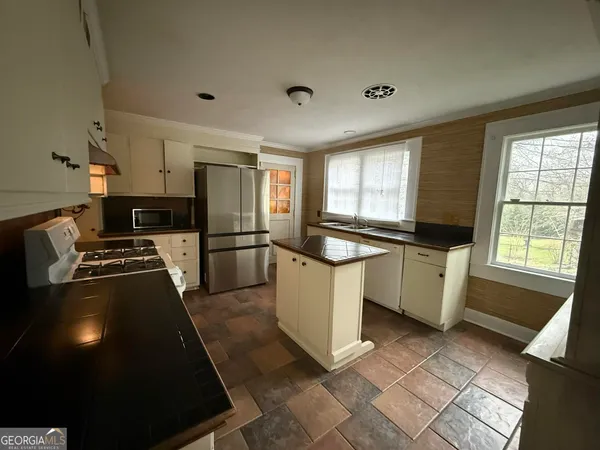 a kitchen with granite countertop a sink a counter top space and stainless steel appliances