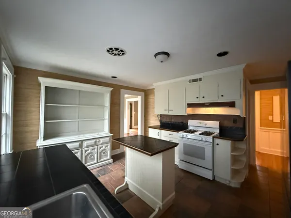 a kitchen with granite countertop a stove and white cabinets