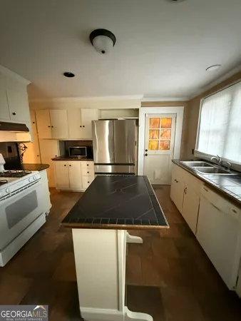 a kitchen with granite countertop a stove and white cabinets