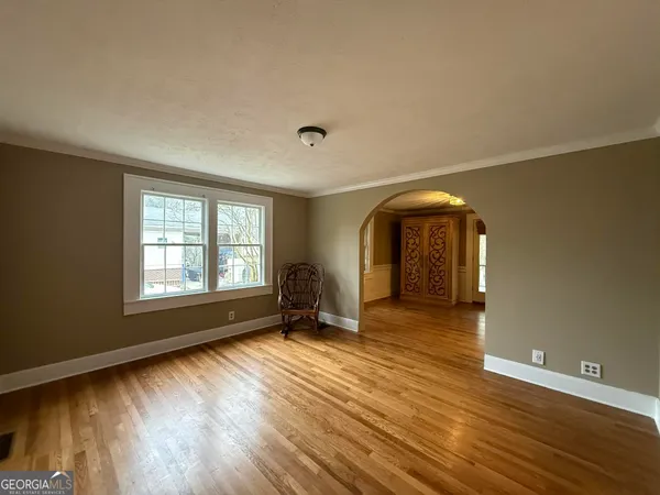 a view of an empty room with glass door and wooden floor