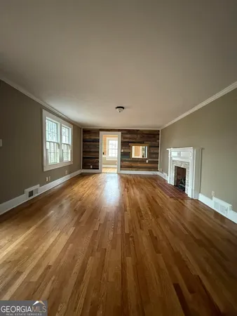 a view of empty room with fireplace and wooden floor