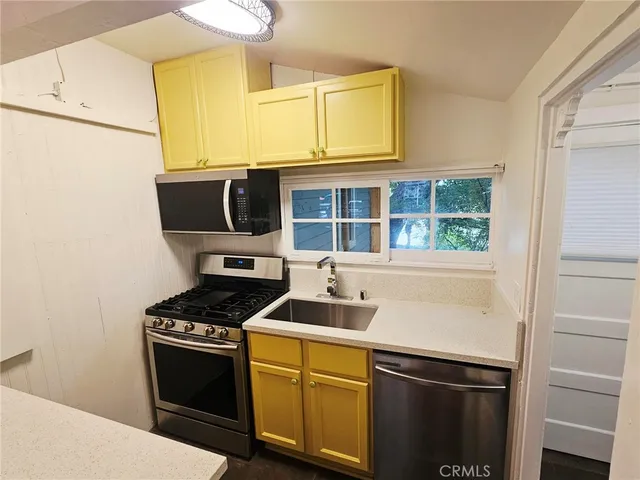 a kitchen with stainless steel appliances a stove a microwave and a sink