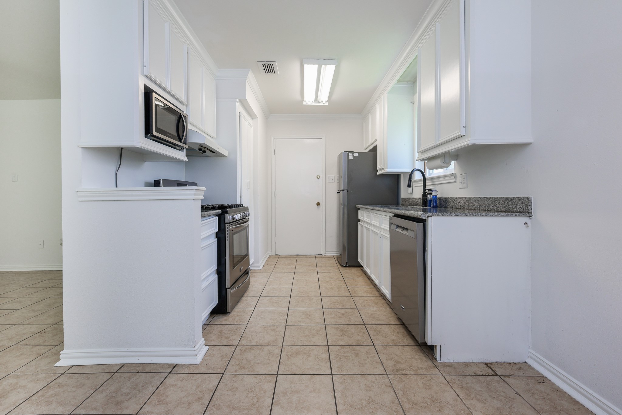 4823 Connorvale Road Houston, TX 77039 - Photo 11 of 26 A modern kitchen with white cabinetry, stainless steel appliances, and granite countertops.