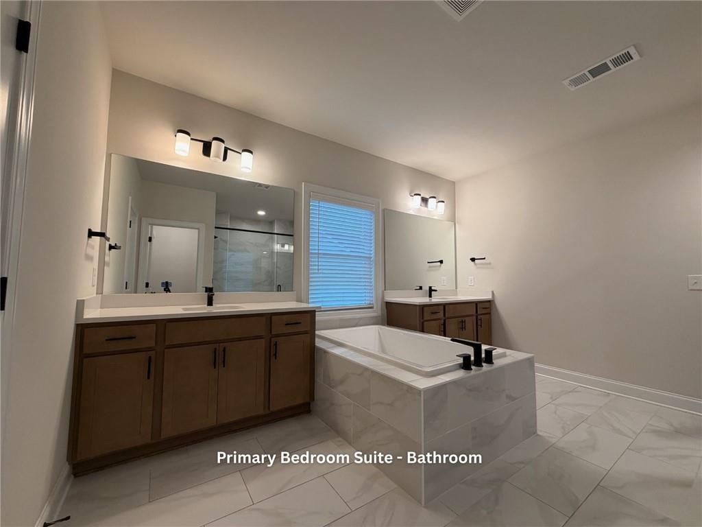 3770 Andover Street Cumming, GA 30028 - Photo 28 of 52 a spacious bathroom with a double vanity sink a mirror and a bathtub