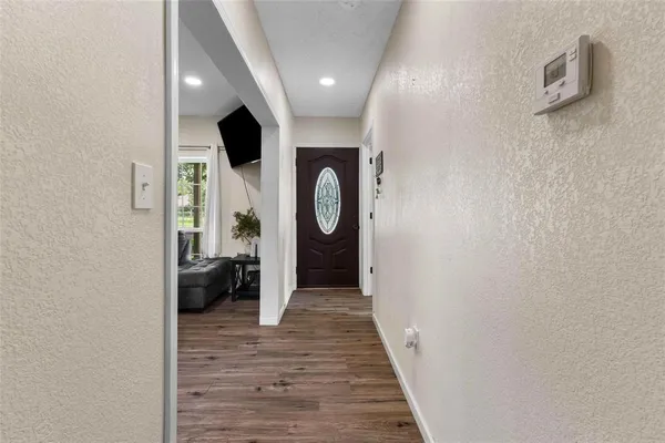 a view of a hallway with wooden floor and a bathroom