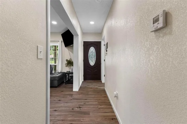 a view of a hallway with wooden floor and a bathroom
