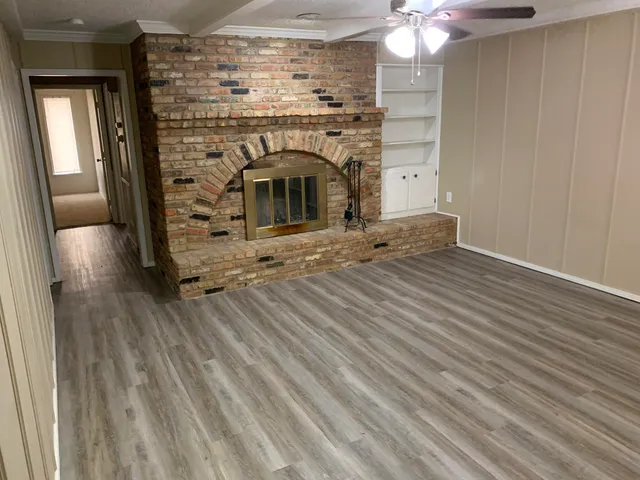 an empty room with wooden floor fireplace and windows