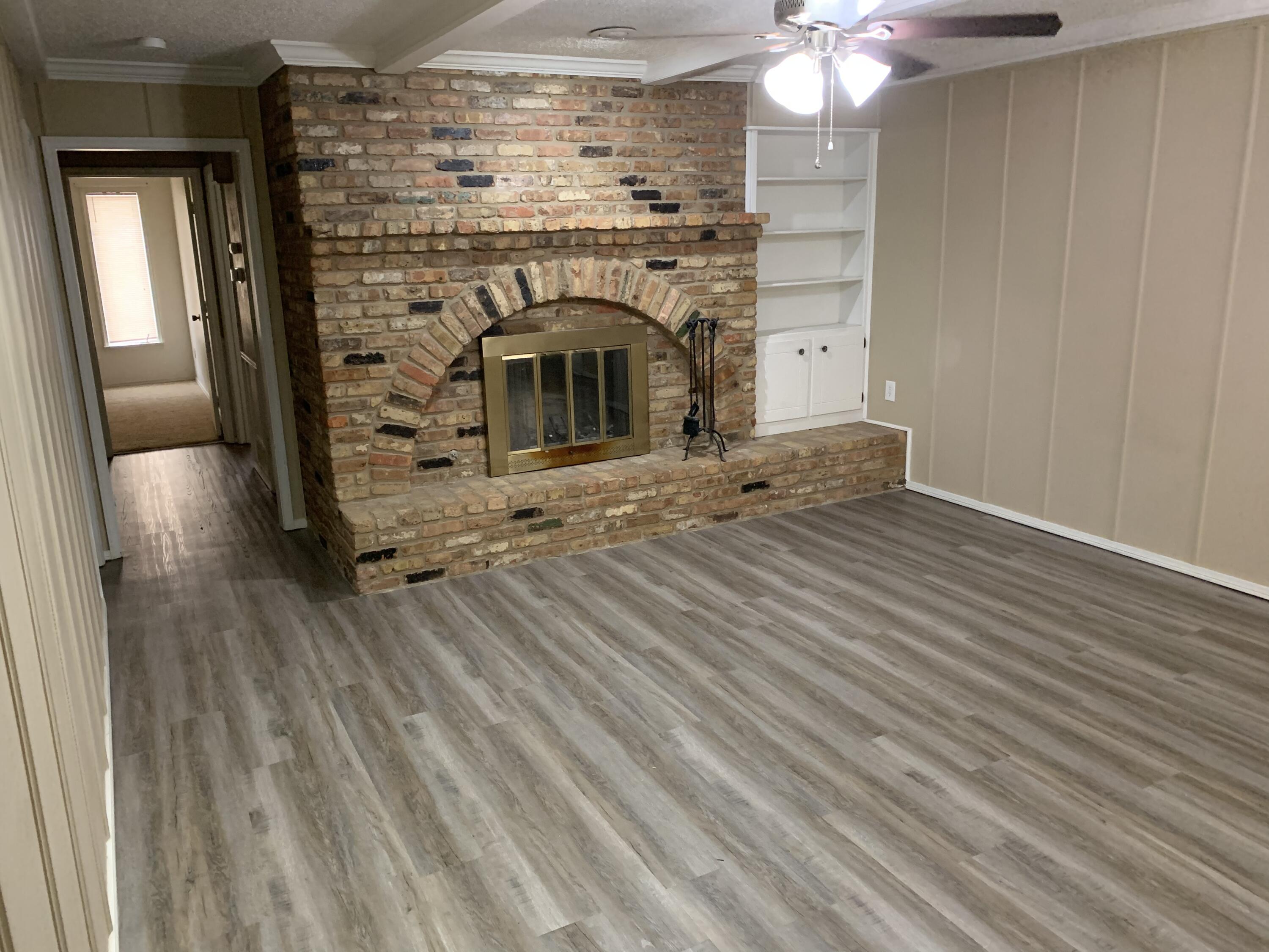 3216 74th Street, Unit B Lubbock, TX 79423 - Photo 1 of 11 an empty room with wooden floor fireplace and windows