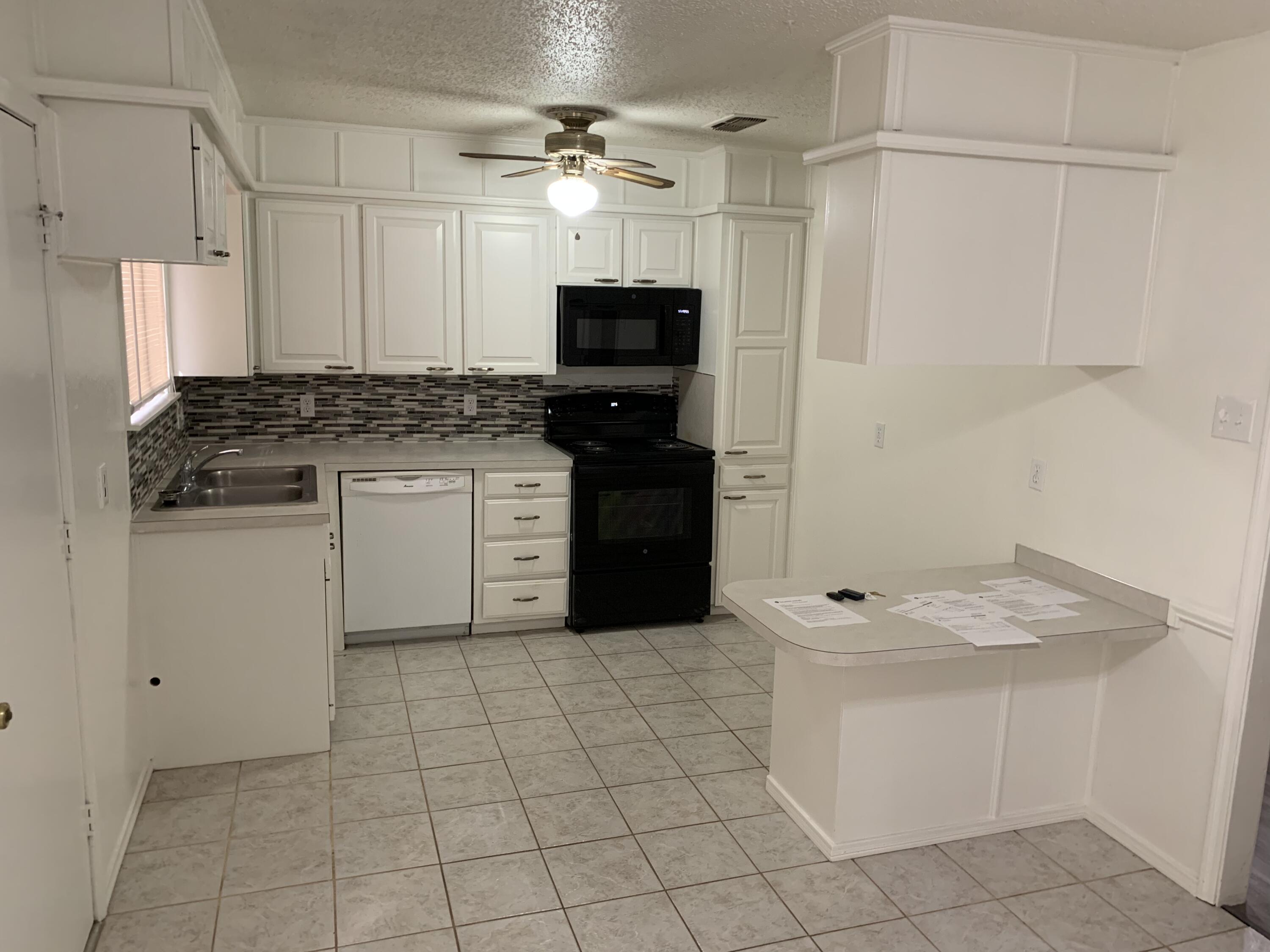 3216 74th Street, Unit B Lubbock, TX 79423 - Photo 4 of 11 a kitchen with stainless steel appliances granite countertop a stove a sink and a refrigerator